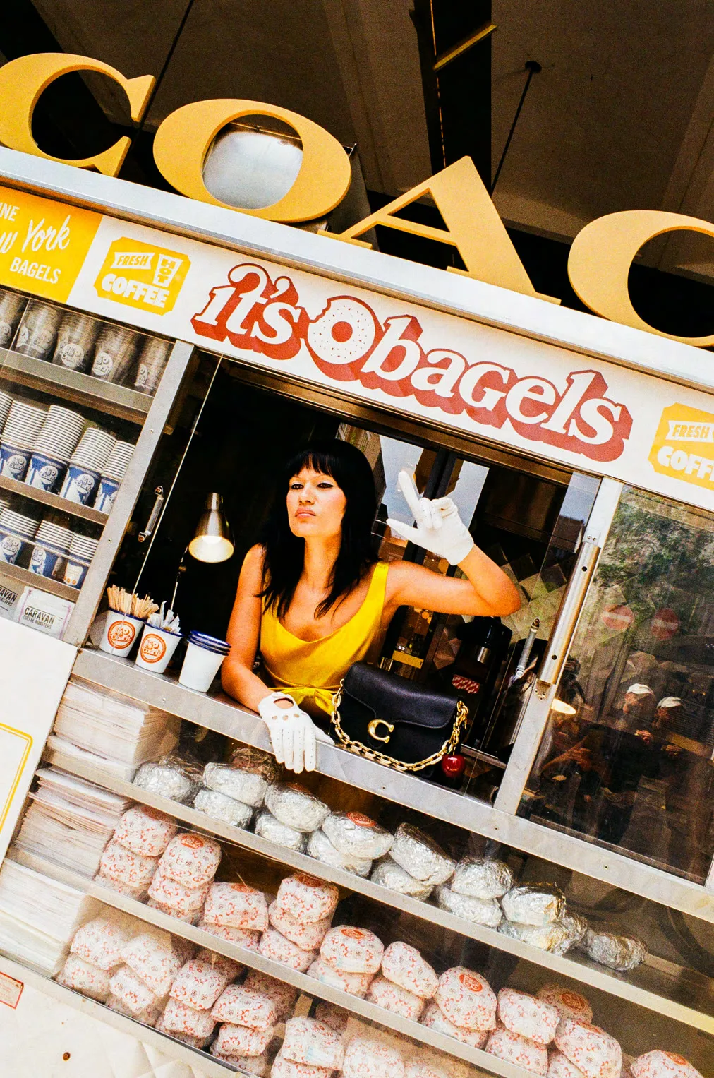 Server leaning out of the Coach × It's Bagels cart