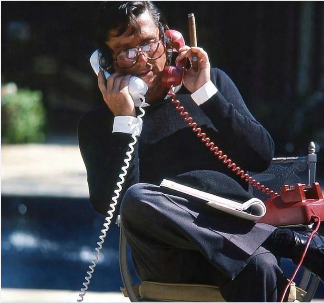 Howie Kahn on two phones with a cigar