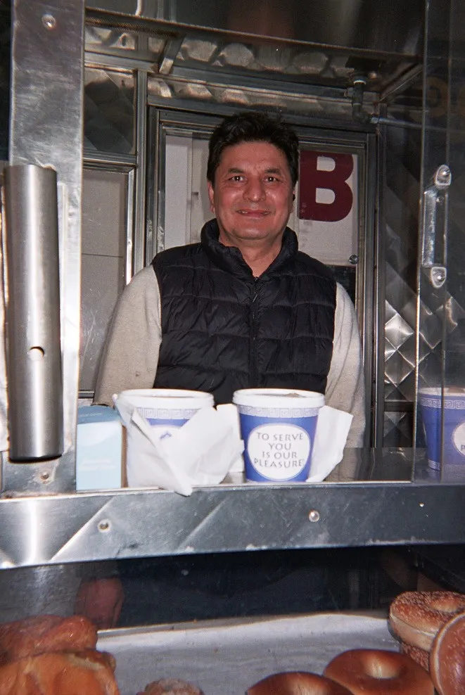Cart vendor with coffee cups that read 'To serve you is our pleasure'